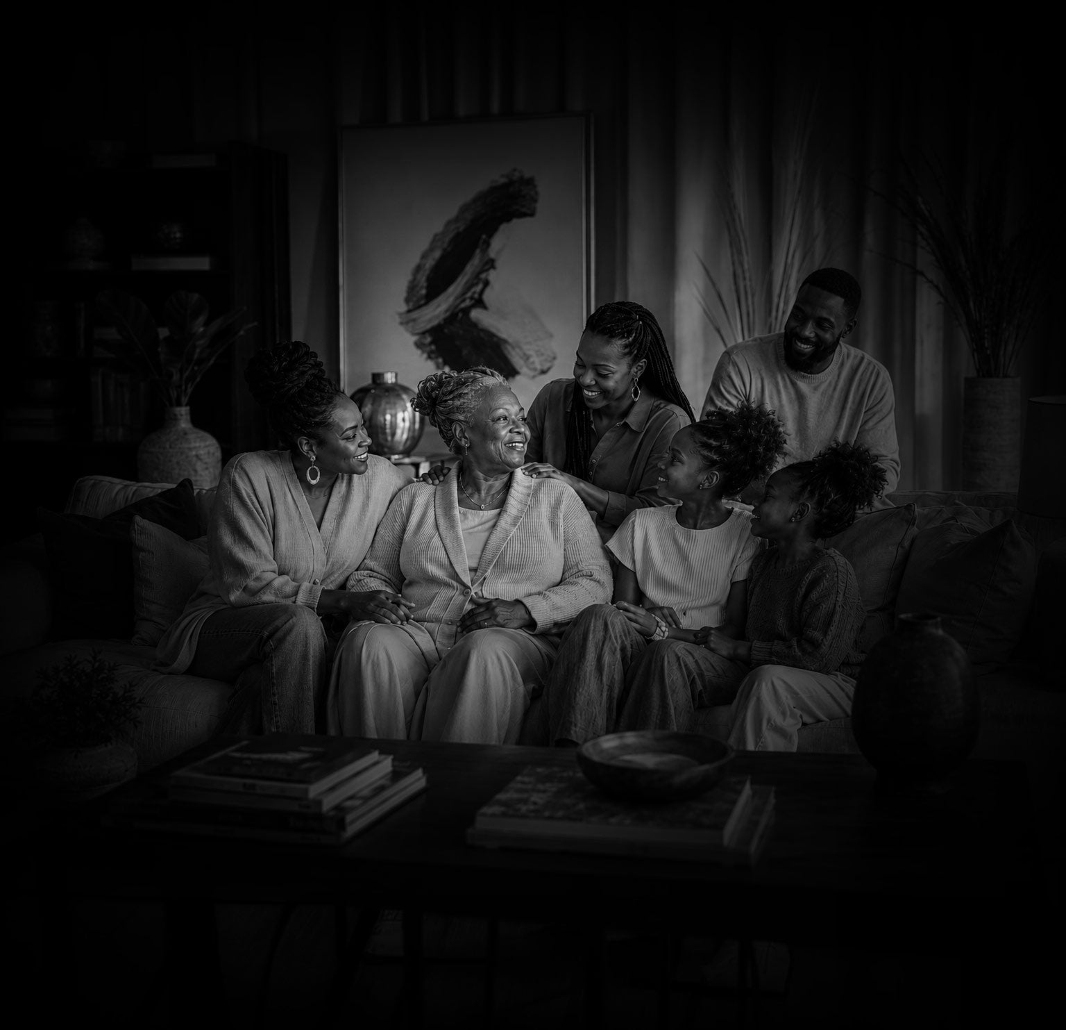 Black and white photo of a family sitting together in a dimly lit room.